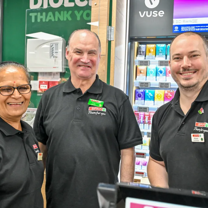 Smiling staff members standing together in a SPAR convenience store.